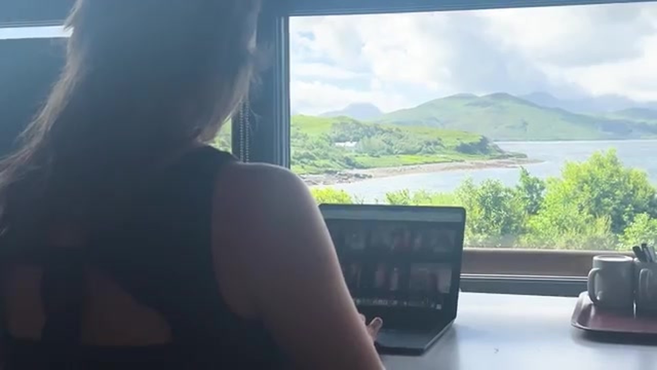 Milly 在窗前开视频会议，窗外是海湾