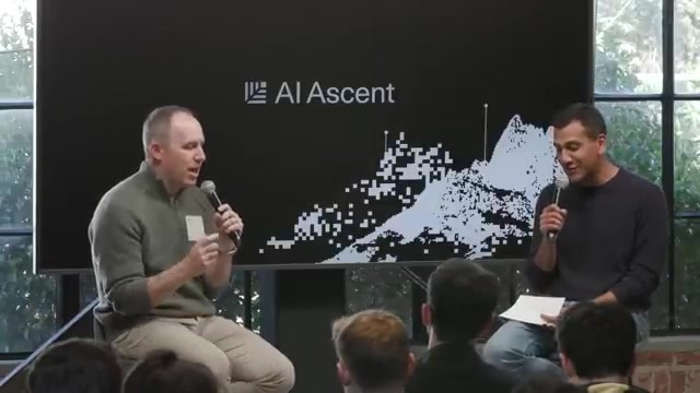现场问答环节：Bret Taylor（左）与主持人（右）持麦对谈，台下听众围坐