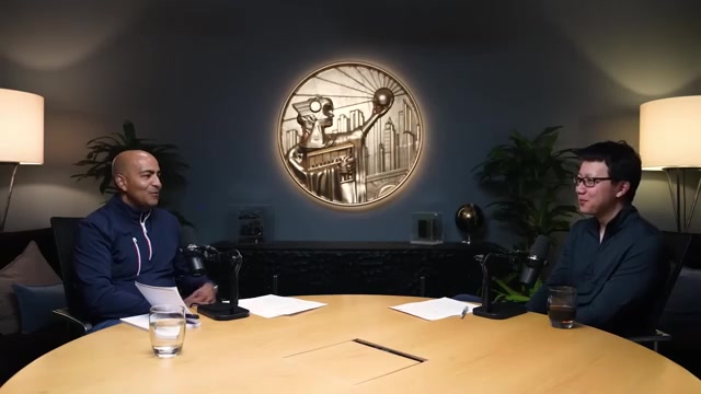 本期对谈：左为主持人 Anish Acharya（a16z 普通合伙人），右为嘉宾 Peter Yang（Roblox PM、X/YouTube 高产创作者），背景墙上是 a16z 标志性的「未来之城」铜质徽章——The a16z Show 演播室